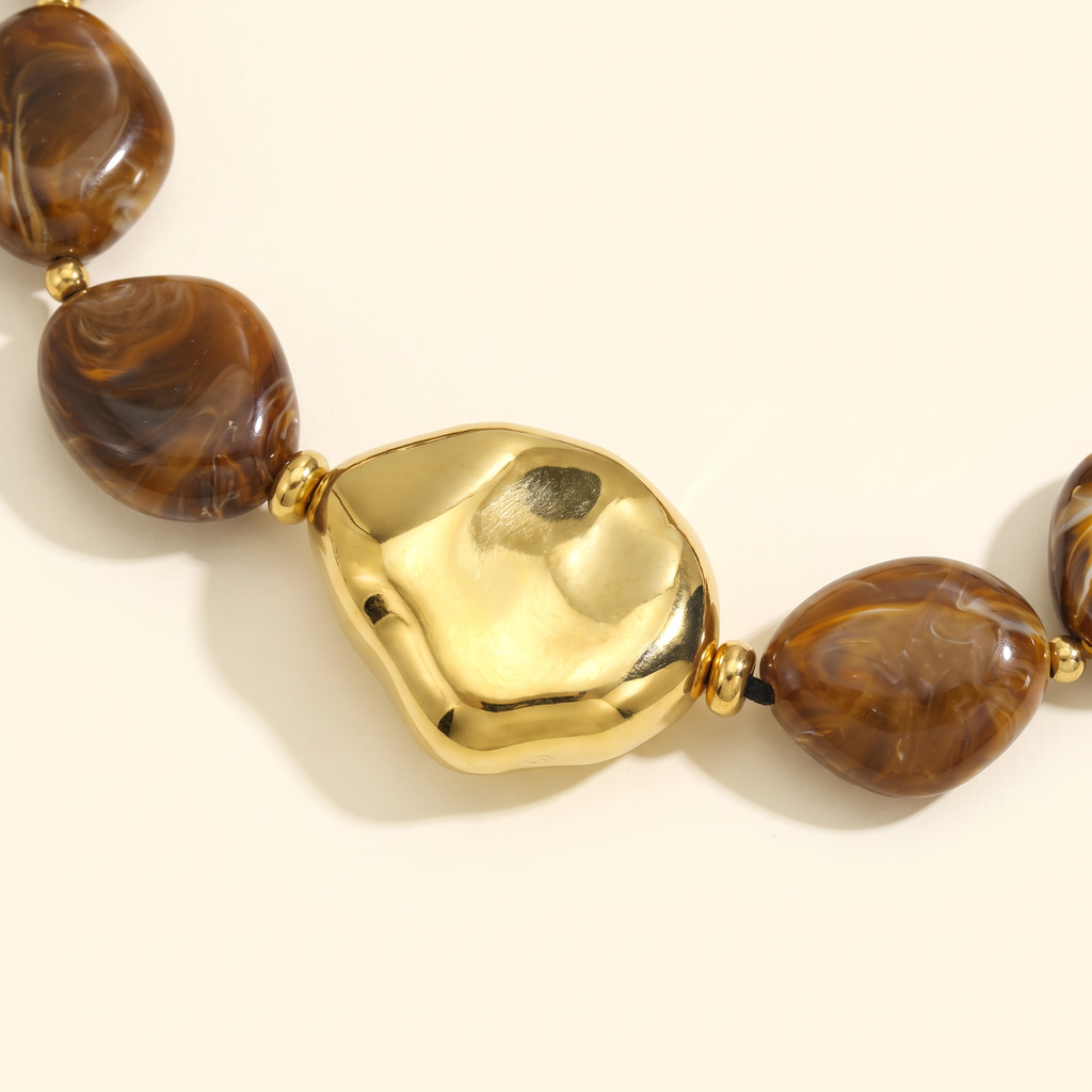 Collier de perles effet marbré de forme plate, détail du motif, marron