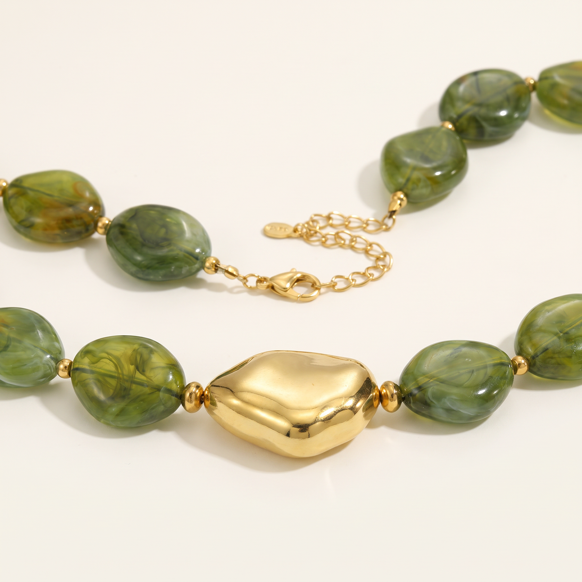 Collier de perles effet marbré de forme plate, détail du motif, kaki