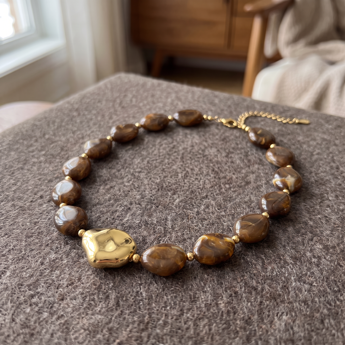 Collier de perles effet marbré de forme plate, porté en tenue, marron