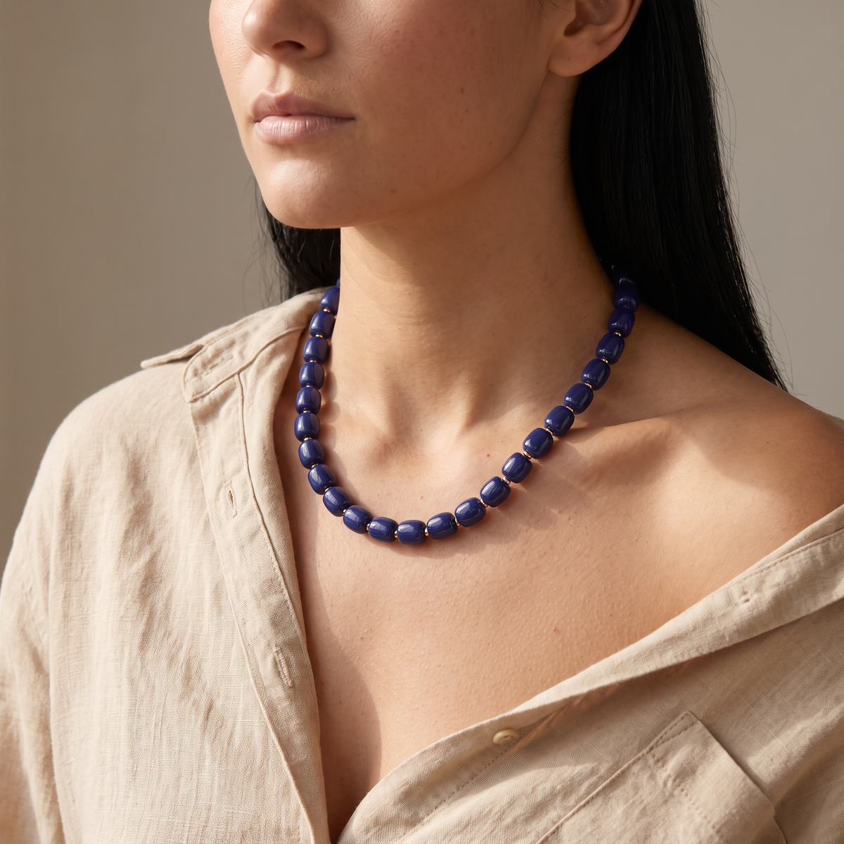 Collier de perles doré, porté mi-corps, bleu marine