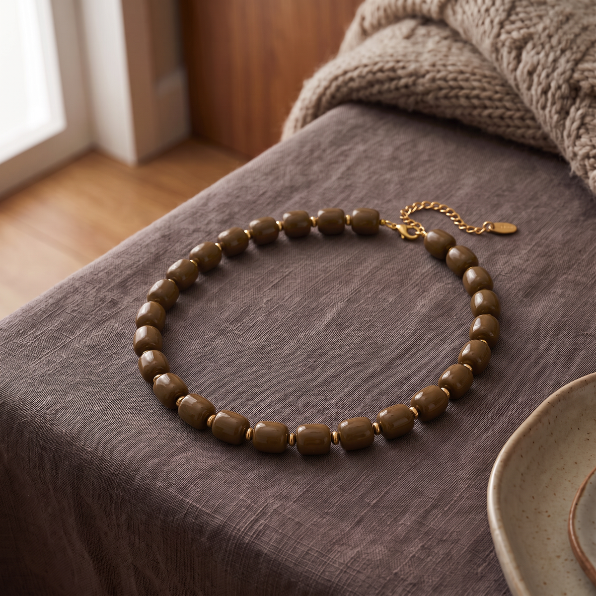 Collier de perles doré, porté en tenue, marron
