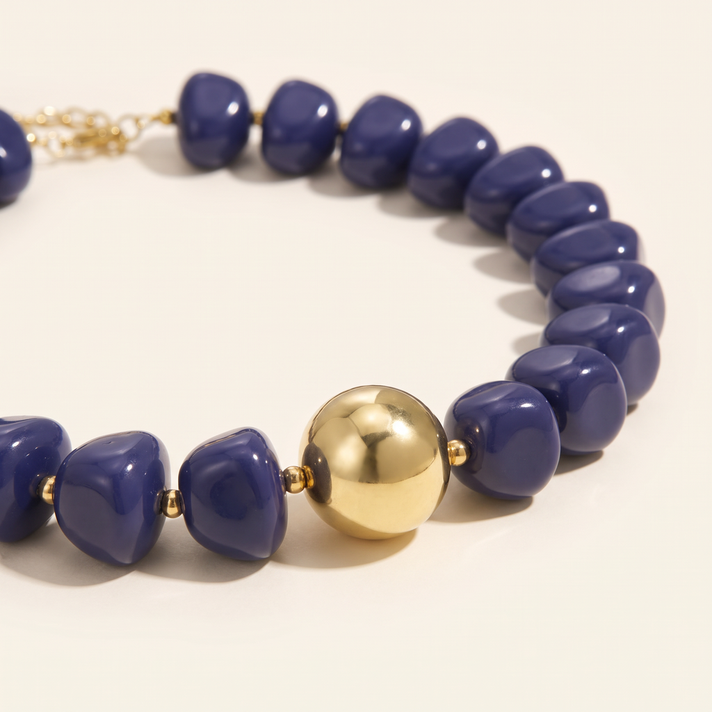 Collier de perles doré à sphères, détail du motif, bleu foncé