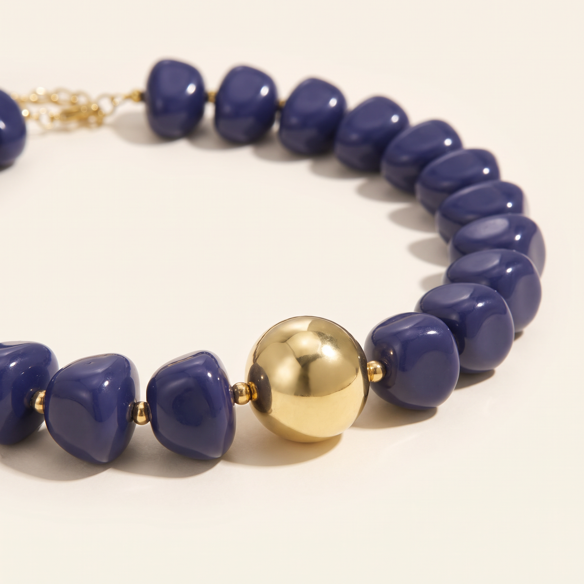 Collier de perles doré à sphères, détail du motif, bleu foncé