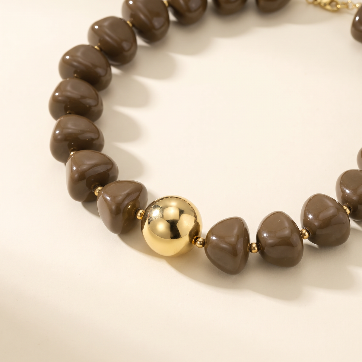Collier de perles doré à sphères, détail du motif, brun foncé