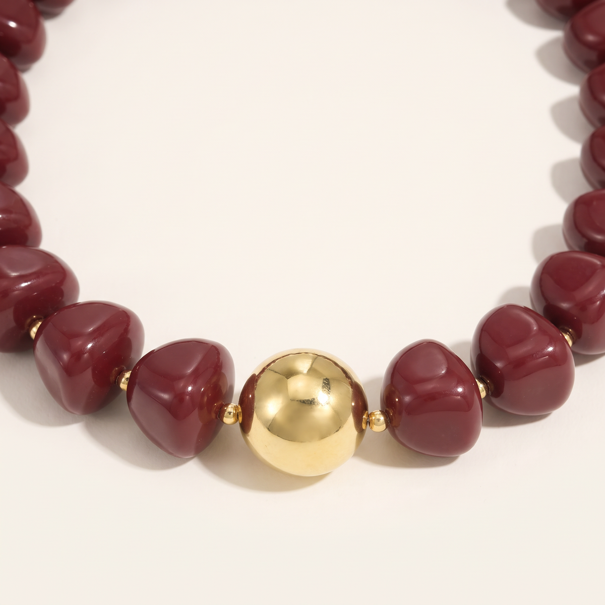 Collier de perles doré à sphères, détail du motif, bordeaux