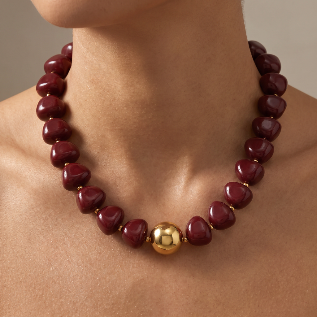 Collier de perles doré à sphères, porté, bordeaux