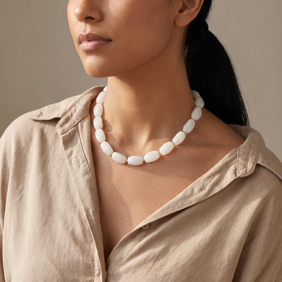 Collier de perles à forme organique, porté mi-corps, blanc cassé