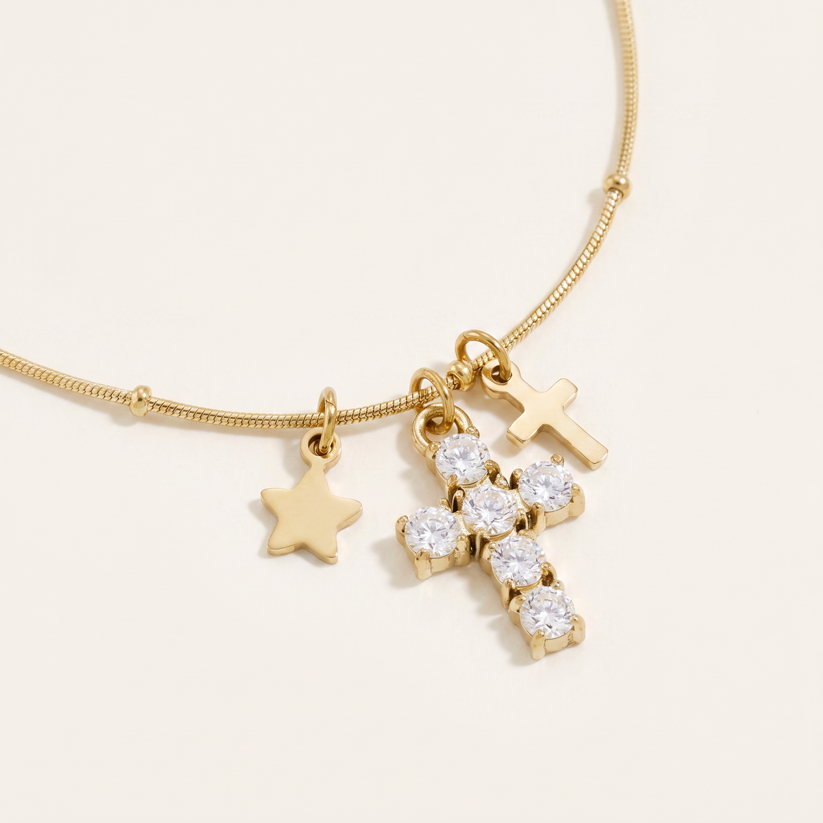 Collier croix et étoile à strass, détail du motif, doré