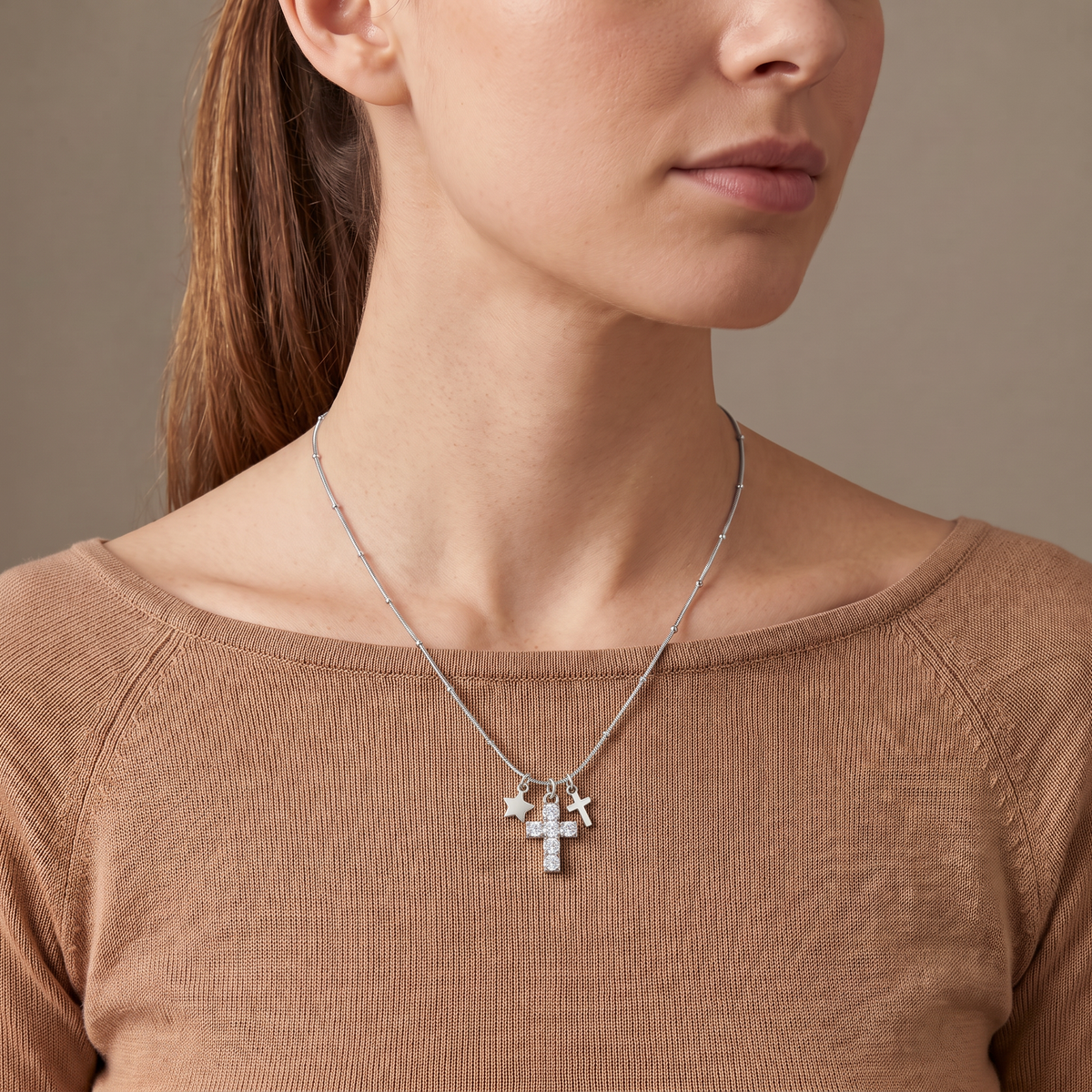 Collier croix et étoile à strass, porté mi-corps, argenté