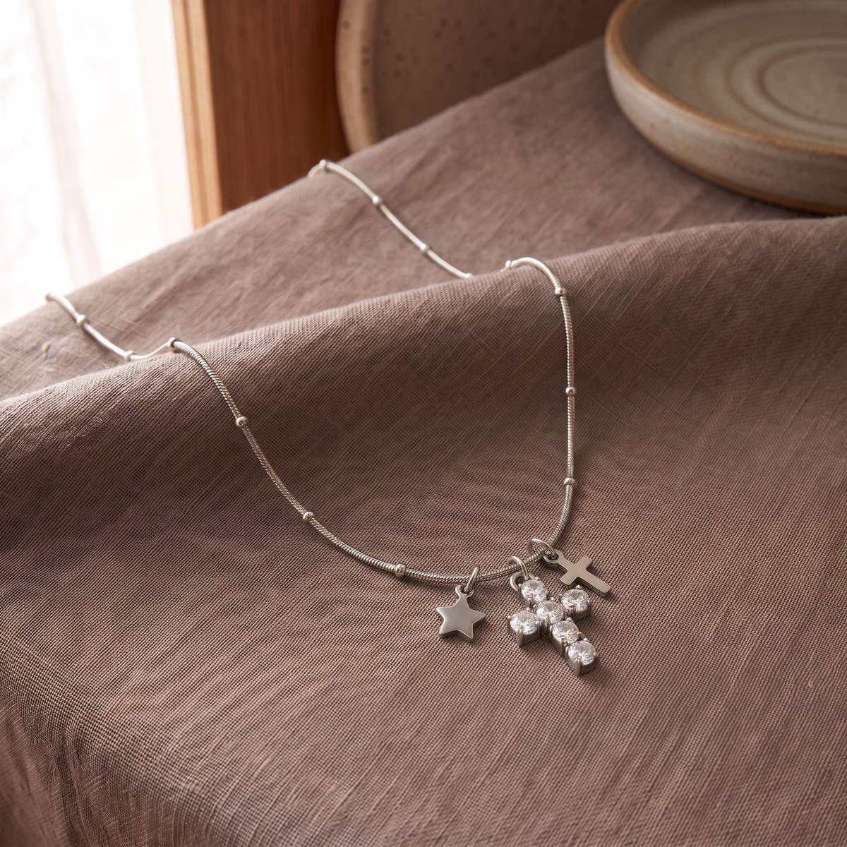 Collier croix et étoile à strass, porté en tenue, argenté