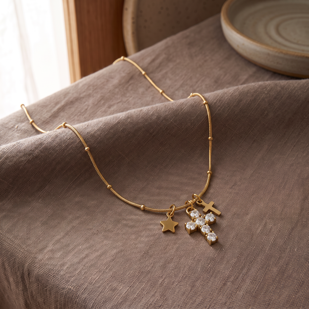Collier croix et étoile à strass, porté en tenue, doré