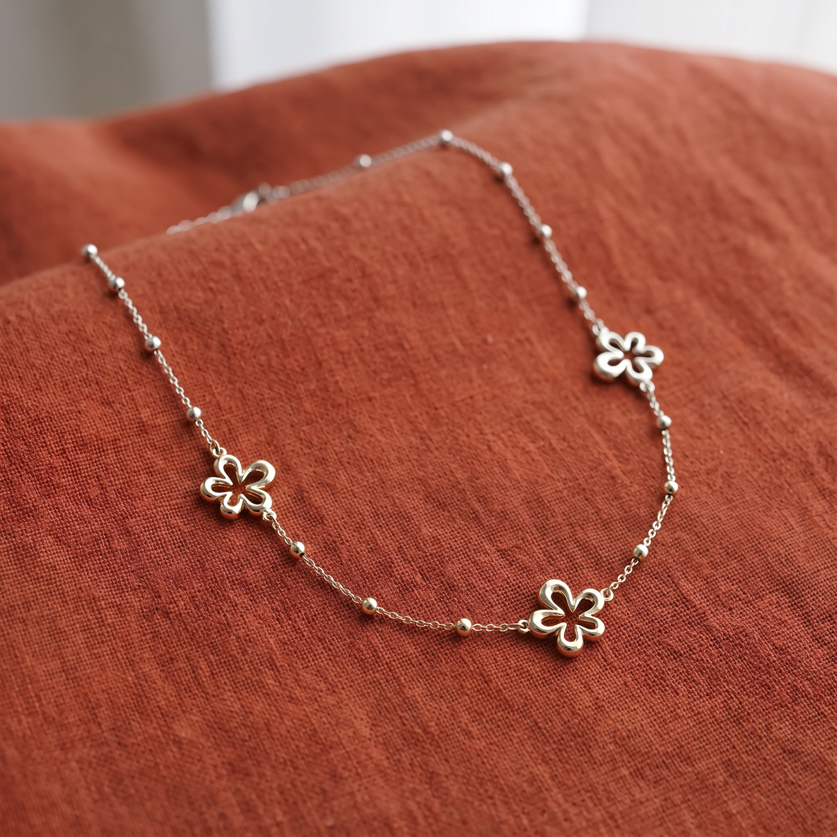 Collier charms fleur à motif ajouré, porté en tenue, argenté