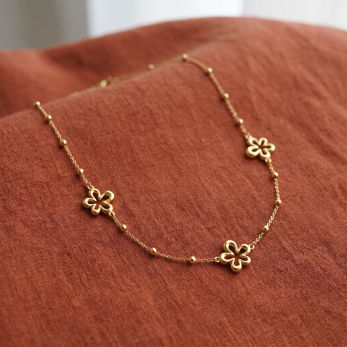 Collier charms fleur à motif ajouré, porté en tenue, doré