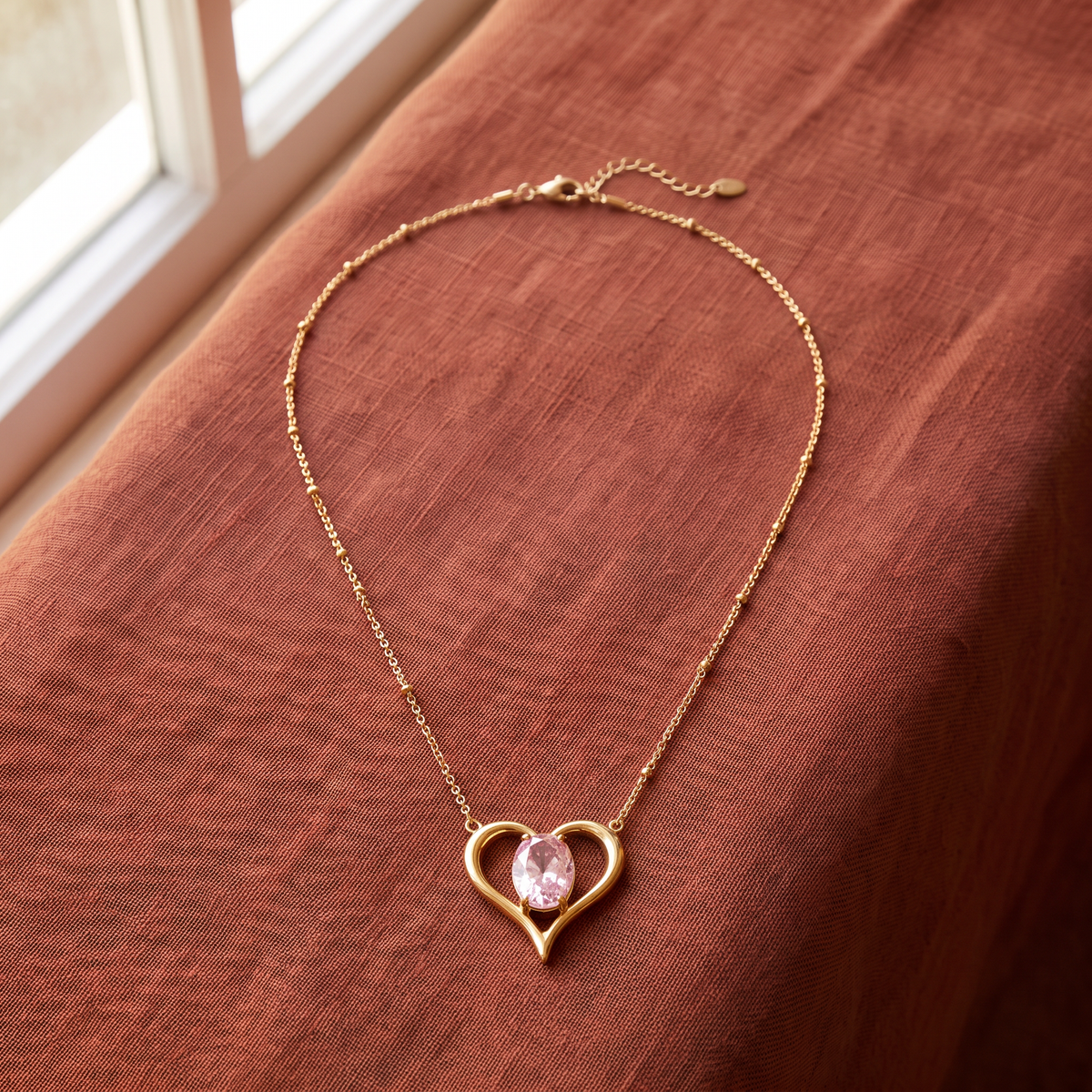 Collier cœur doré à motif ajouré à strass, porté en tenue, rose