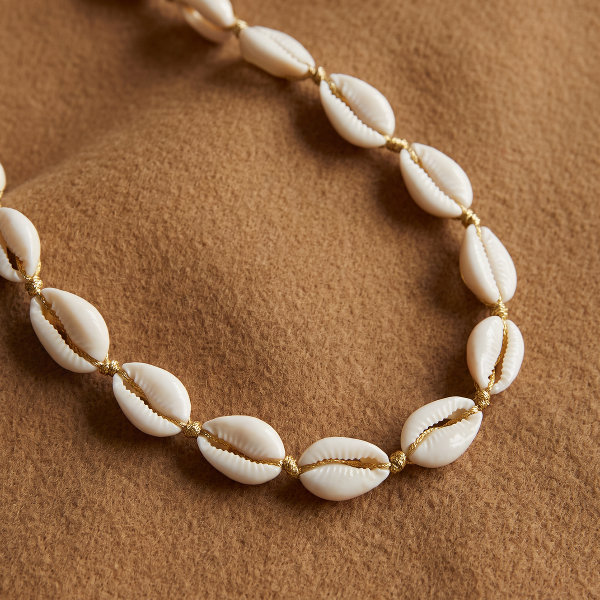 Collier ras de cou coquillage doré, porté en tenue