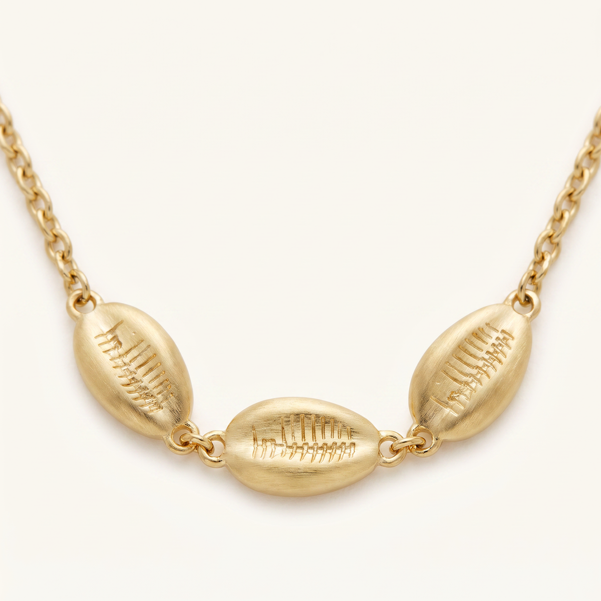 Collier cauri sur chaîne, détail du motif, doré