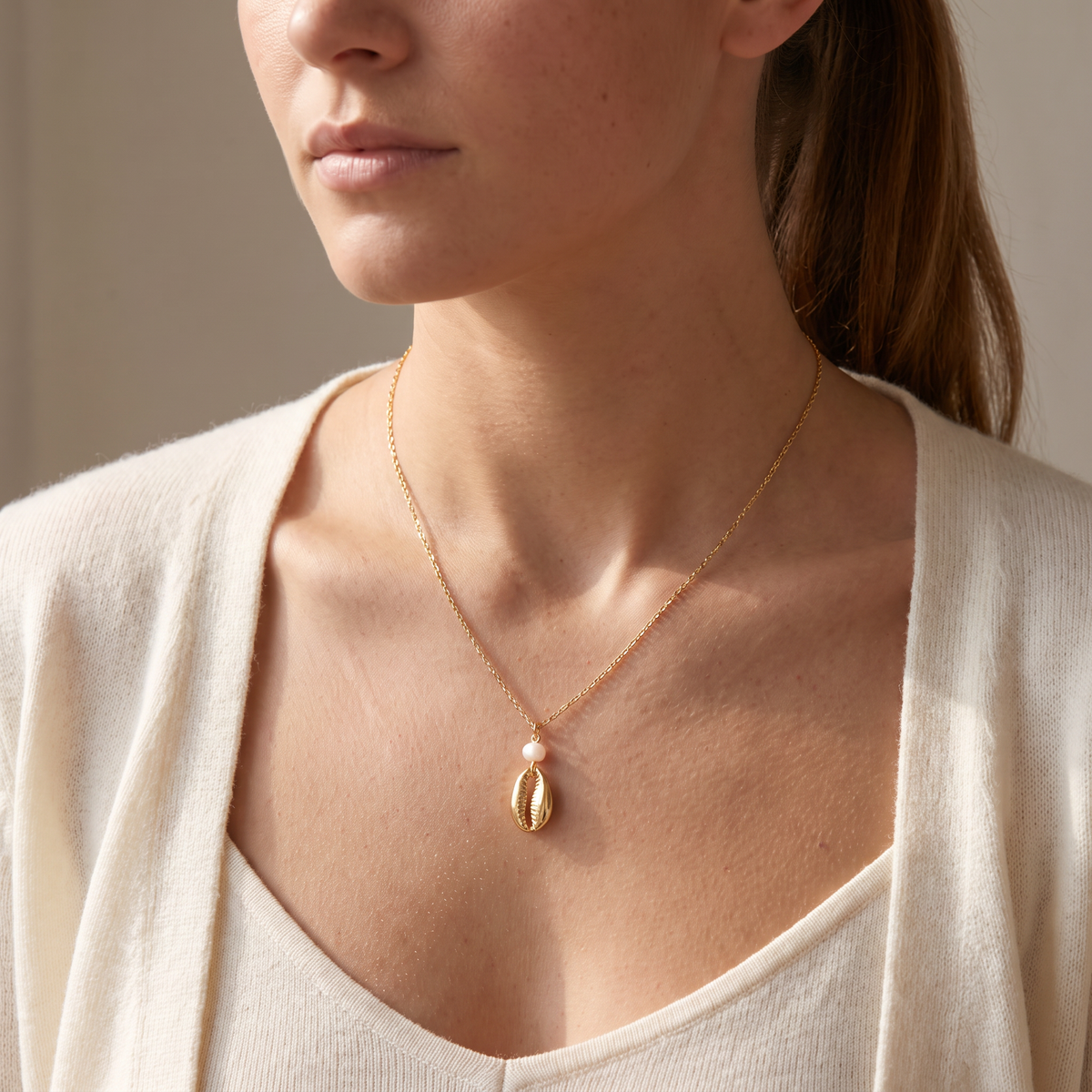 Collier cauri en perles, porté mi-corps, doré
