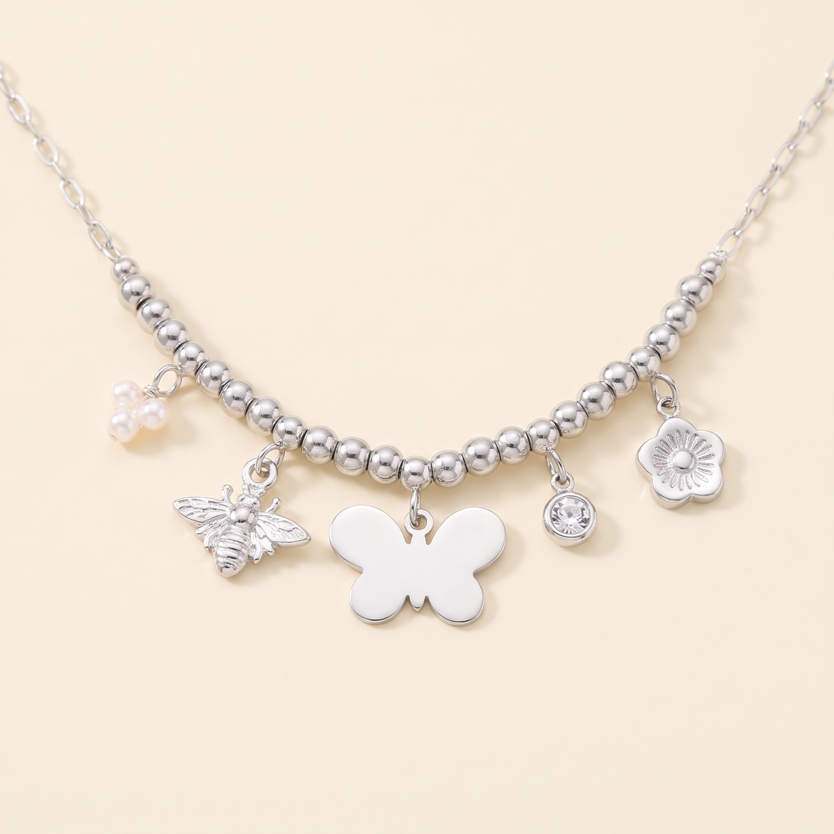 Collier charms fleur et papillon, détail du motif, argenté
