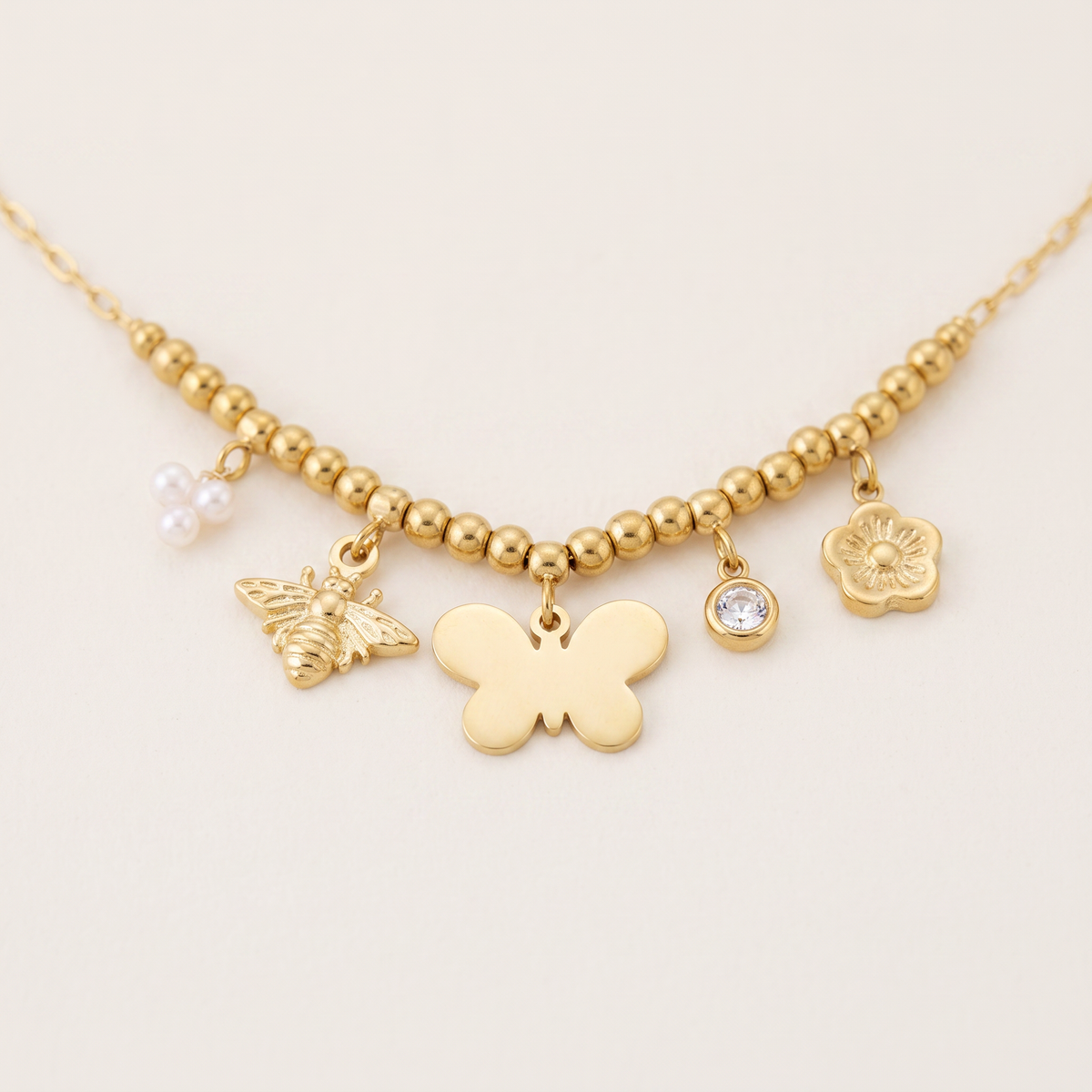 Collier charms fleur et papillon, détail du motif, doré